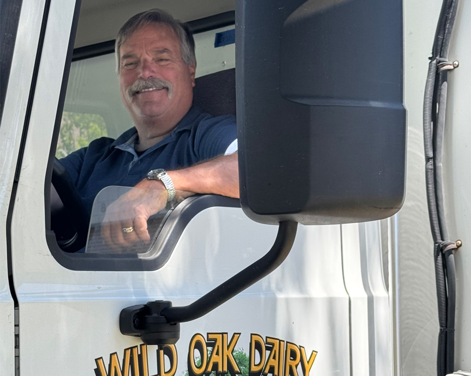 Wild Oak Dairy driver smiling from the cab of a Luther Brothers Distributors delivery truck